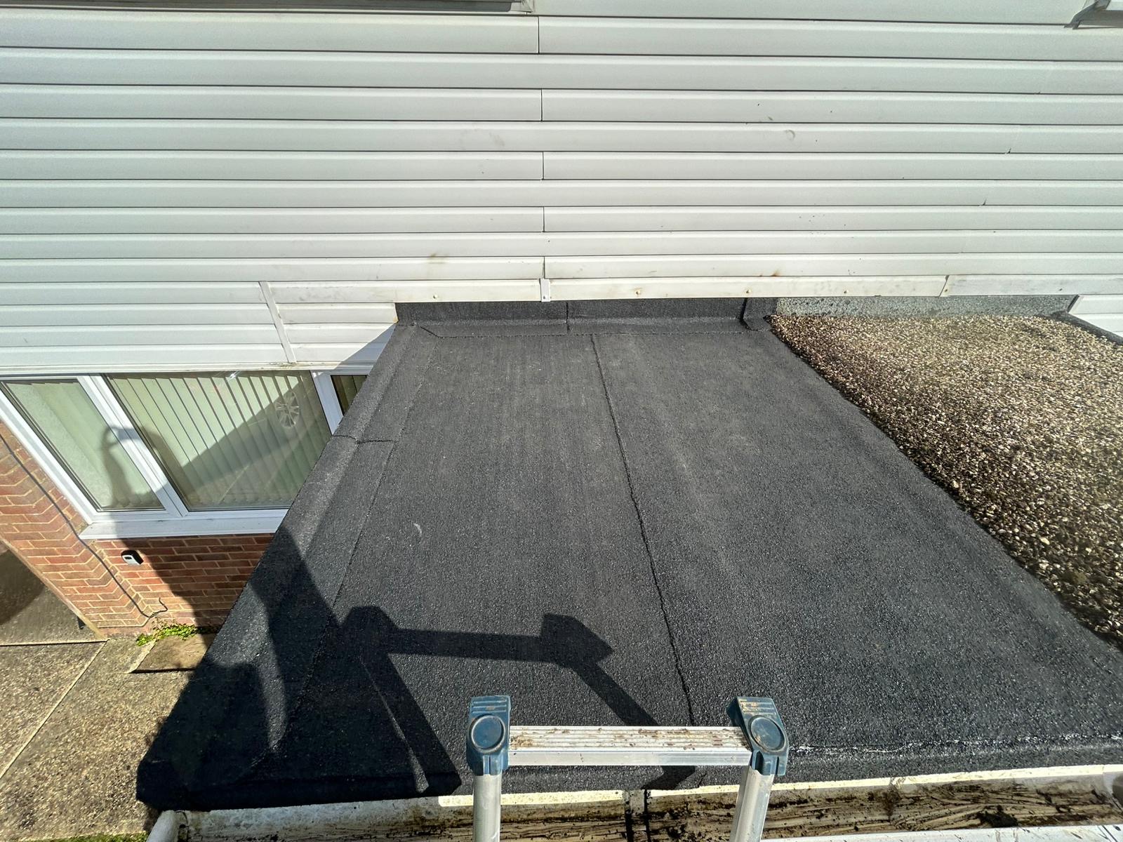Newly laid dark grey felt roof on a residential extension, carried out by JP Roofing