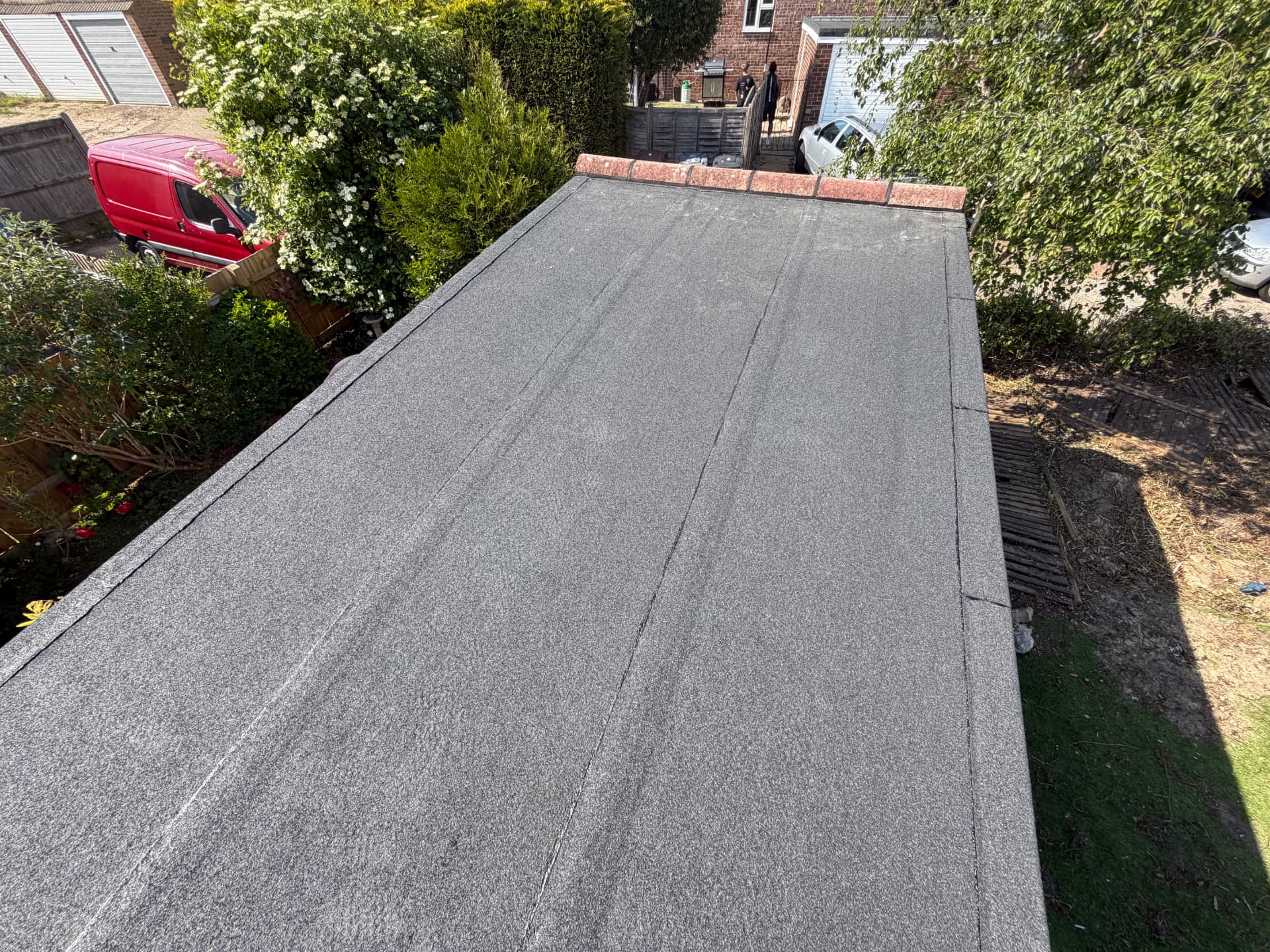 Long grey felt roof with a red tile edge, seen from above, completed by JP Roofing in East Sussex